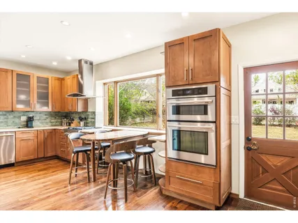 a view of a kitchen with refrigerator and wooden floor