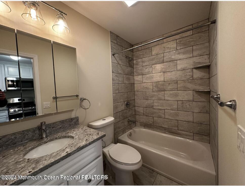 606 Ocean Road, Unit D Point Pleasant, NJ 08742 - Photo 2 of 5 a bathroom with a granite countertop sink toilet and shower