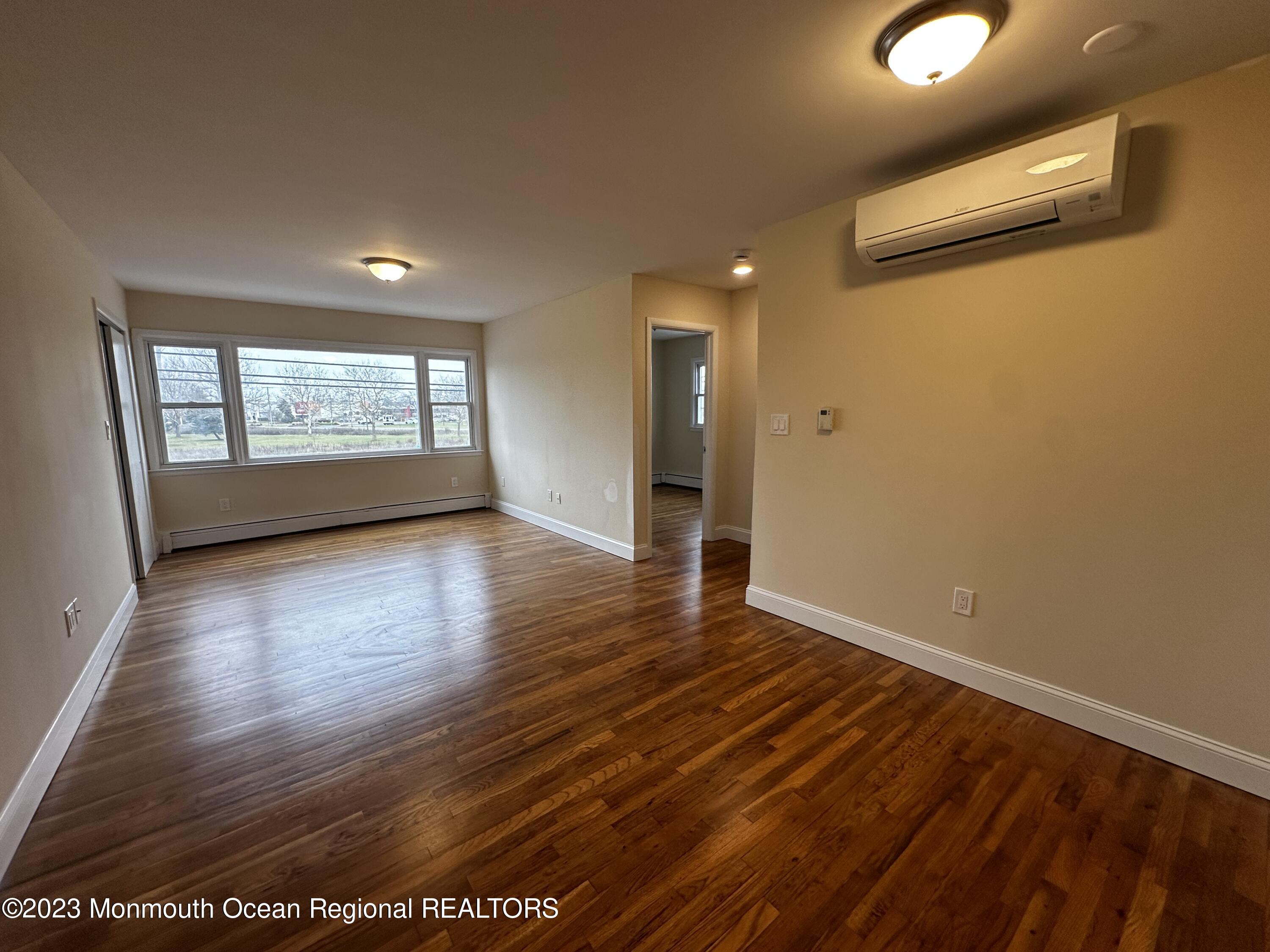 606 Ocean Road, Unit D Point Pleasant, NJ 08742 - Photo 5 of 5 an empty room with wooden floor and windows