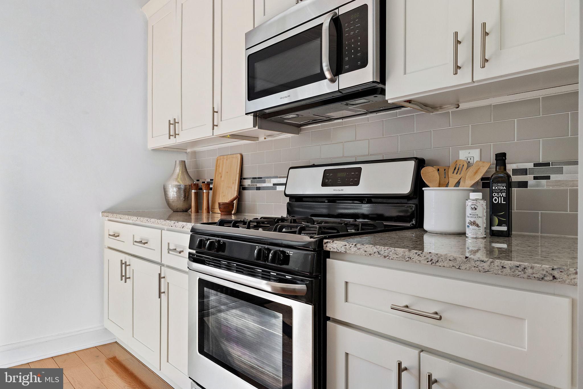 432 Mercy Street Philadelphia, PA 19148 - Photo 9 of 36 a kitchen with granite countertop white cabinets stainless steel appliances and wooden floor