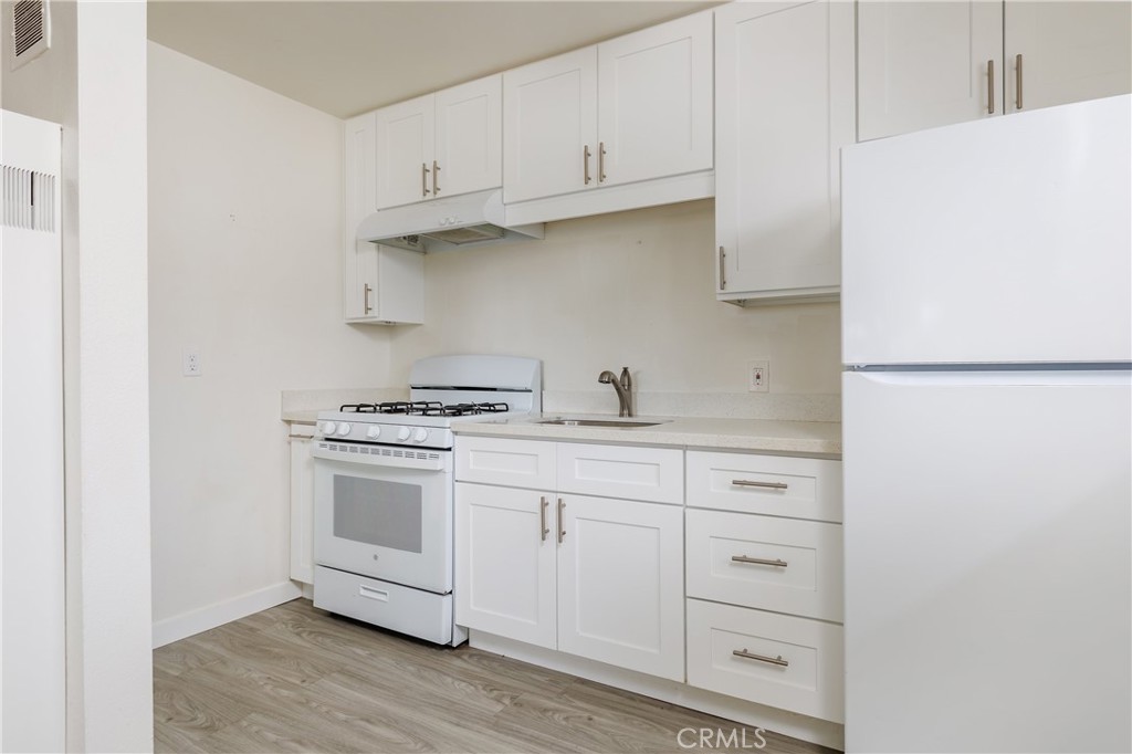 321 North K Street Lompoc, CA 93436 - Photo 8 of 32 a kitchen with white cabinets and a stove with wooden floor