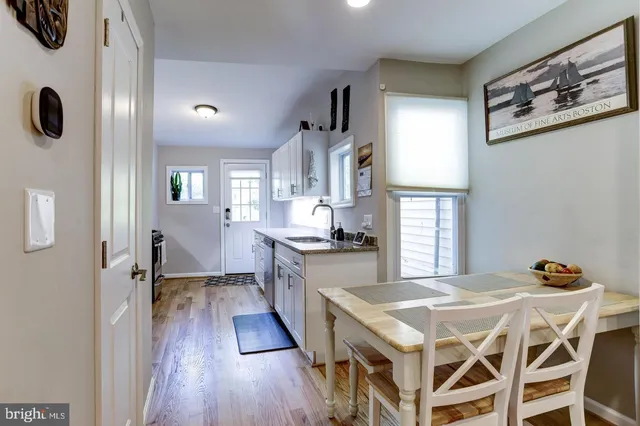 a kitchen with stainless steel appliances granite countertop a stove a refrigerator a sink a dining table and chairs with wooden floor