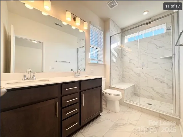 a bathroom with a double vanity sink toilet and shower
