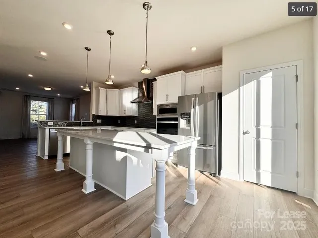 a large kitchen with white cabinets stainless steel appliances and wooden floor