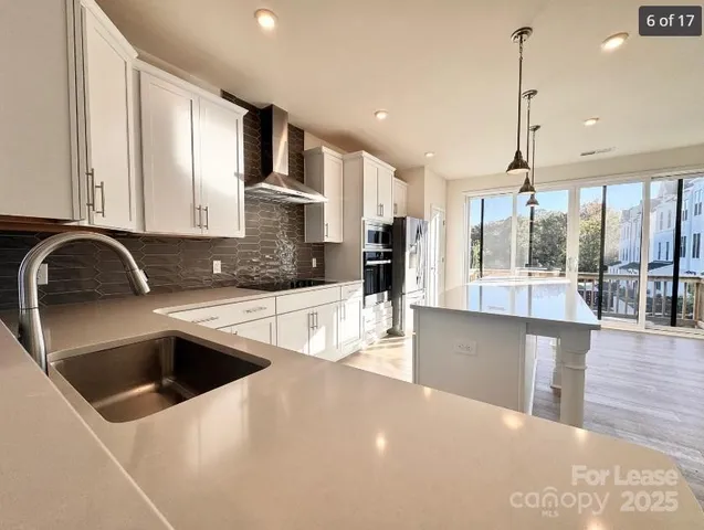 a kitchen with stainless steel appliances granite countertop a sink a stove and a wooden floors