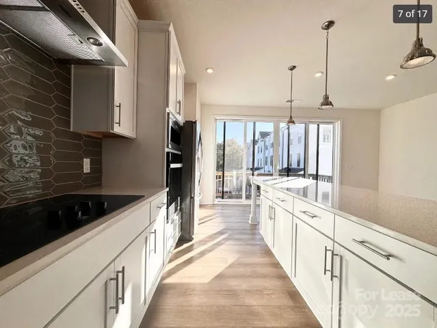 a large kitchen with stainless steel appliances kitchen island a large counter top a stove a chimney a sink and a refrigerator