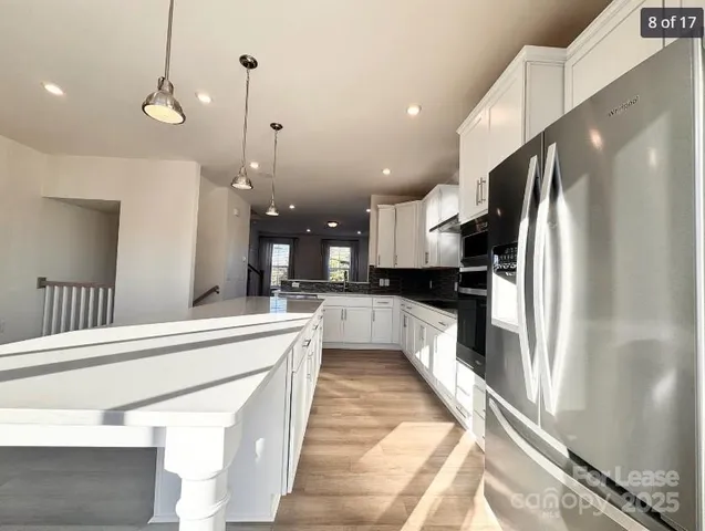 a large kitchen with stainless steel appliances kitchen island a large counter top a stove and a refrigerator