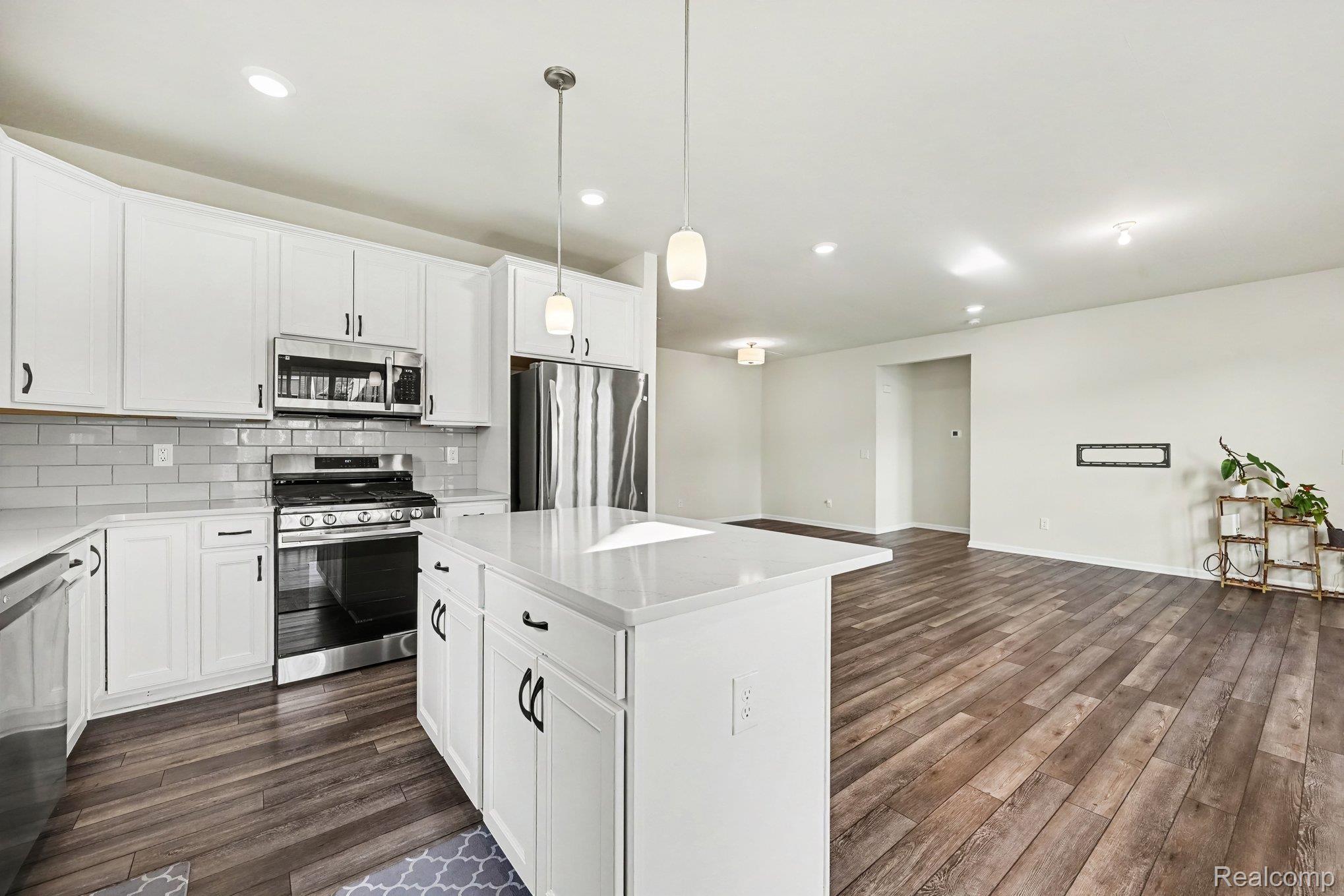 50153 Fowler Road Canton, MI 48188 - Photo 7 of 27 Kitchen featuring white shaker-style cabinetry, stainless steel appliances, a white subway tile backsplash, and a central island with pendant lighting