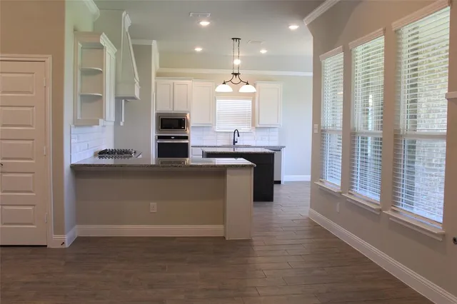 a kitchen with kitchen island granite countertop a stove and a sink