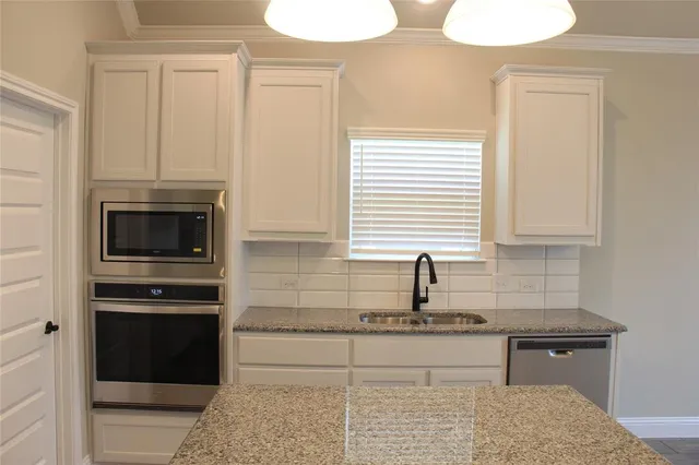 a kitchen with granite countertop white cabinets and stainless steel appliances