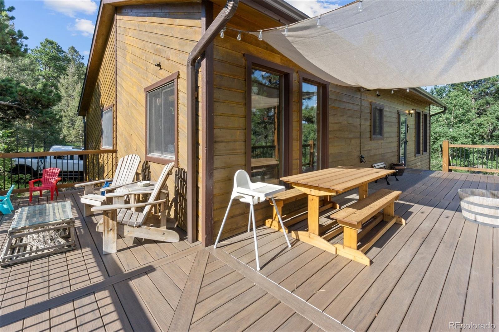 30540 Rand Road Conifer, CO 80433 - Photo 25 of 37 a view of a patio with table and chairs with wooden floor and fence