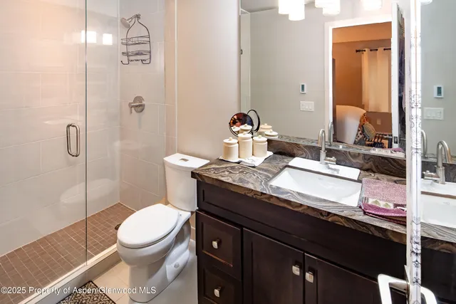 a bathroom with a granite countertop sink a toilet and shower