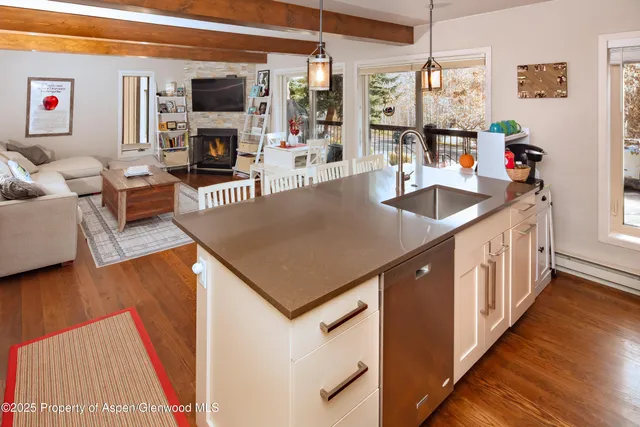a kitchen with stainless steel appliances granite countertop a sink and a living room with wooden floor