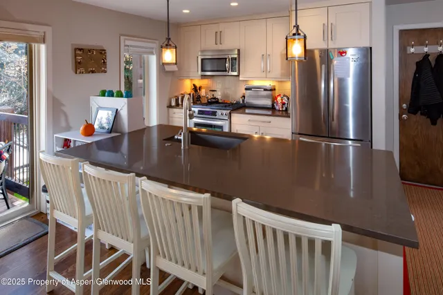 a kitchen with stainless steel appliances granite countertop a refrigerator a stove top oven a sink dishwasher and white cabinets