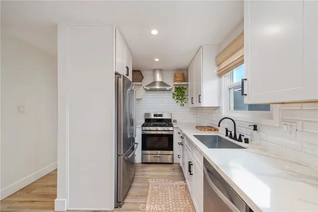 a kitchen with a sink white cabinets and stainless steel appliances
