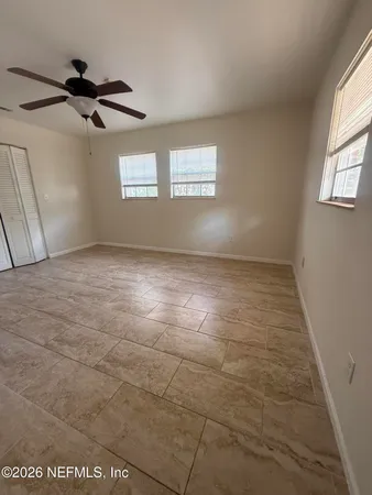 an empty room with windows and fan