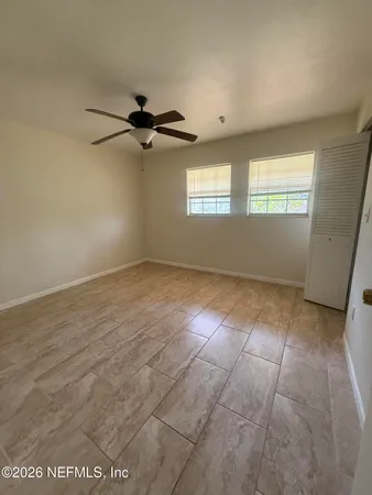 an empty room with windows and fan