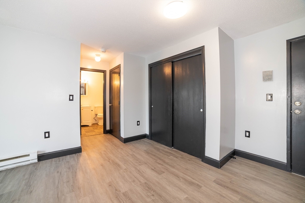 80 Stanton Street, Unit 32 Worcester, MA 01605 - Photo 13 of 20 an empty room with wooden floor and windows