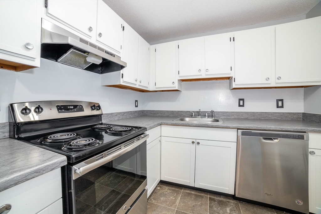 80 Stanton Street, Unit 32 Worcester, MA 01605 - Photo 5 of 20 a kitchen with cabinets stainless steel appliances and wooden floor