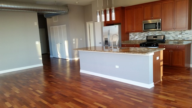 450 Village Center Drive, Unit 414 Burr Ridge, IL 60527 - Photo 3 of 10 a kitchen with stainless steel appliances granite countertop a sink a stove top oven and wooden floors
