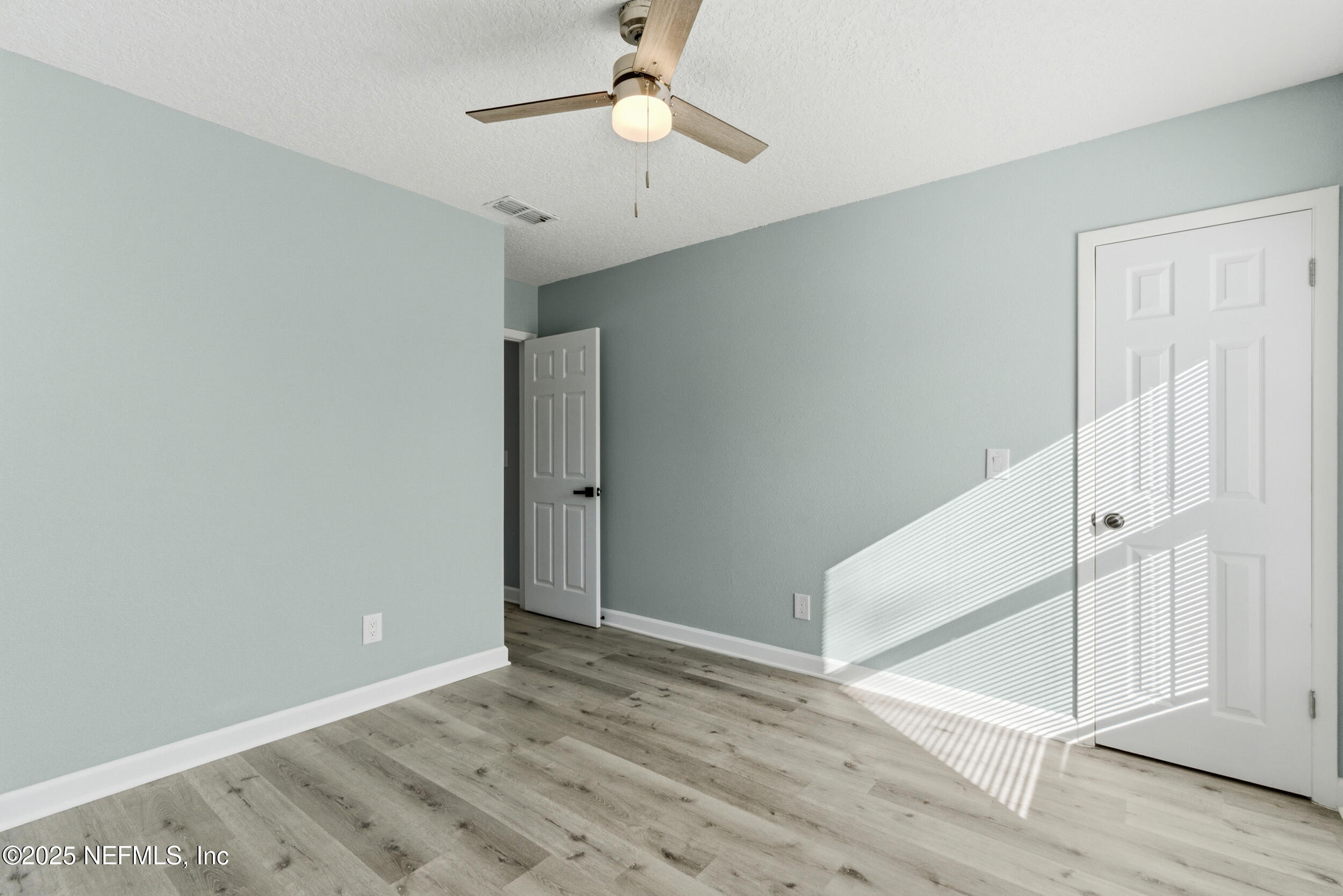 3631 North Ride Drive Jacksonville, FL 32223 - Photo 25 of 30 an empty room with wooden floor fan and windows