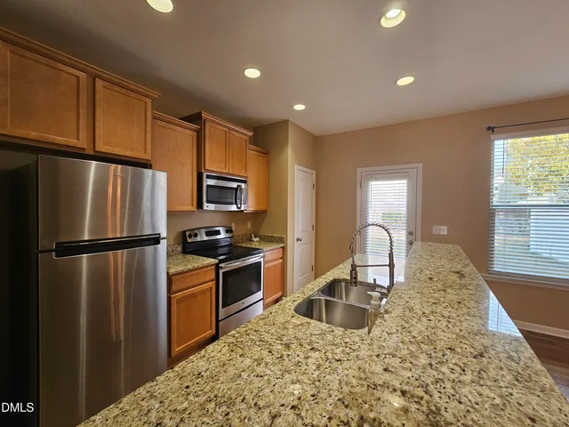 a kitchen with granite countertop a refrigerator and a stove top oven