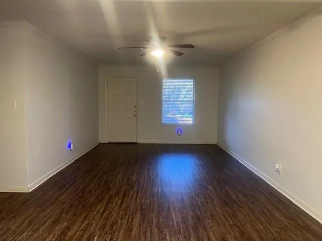 a view of an empty room with wooden floor and a window