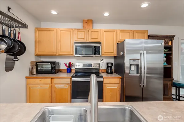 a kitchen with stainless steel appliances granite countertop a refrigerator a stove and a sink with wooden floor