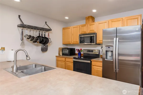 a kitchen with stainless steel appliances granite countertop a refrigerator a stove and a sink with wooden floor