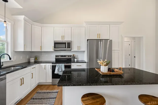 a kitchen with stainless steel appliances granite countertop a sink stove refrigerator and microwave