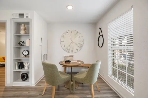 a kitchen with stainless steel appliances granite countertop a table chairs in it and wooden floors