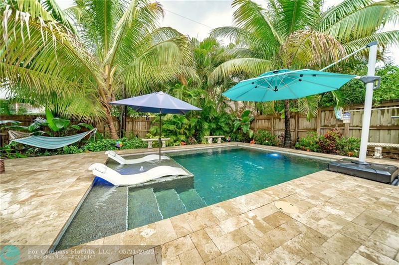 a view of swimming pool with lawn chairs under an umbrella