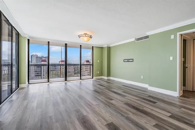 a view of an empty room with glass door and windows
