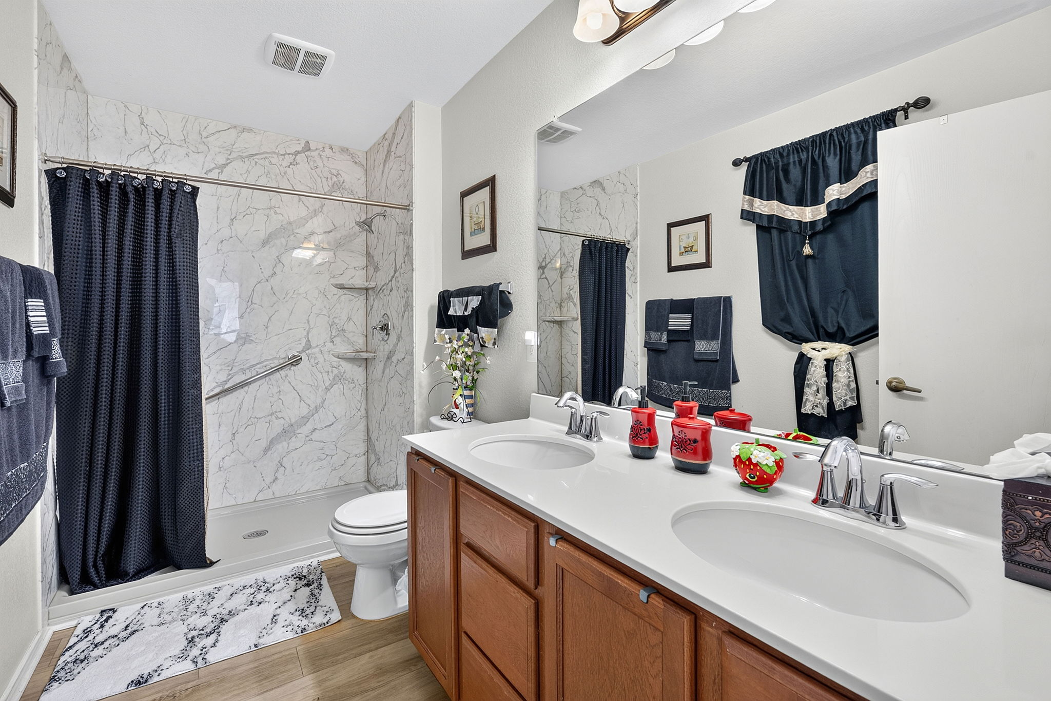 9004 Wiley Way Austin, TX 78747 - Photo 19 of 39 Double vanities and a marble-patterned tub surround define this functional bathroom space.