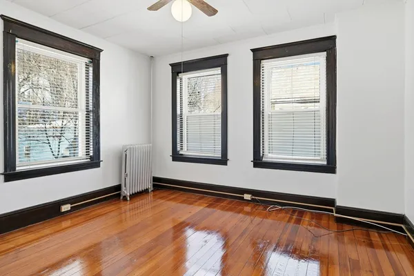 a view of empty room with wooden floor and fan