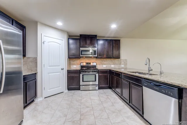 a kitchen with stainless steel appliances granite countertop a refrigerator sink and stove