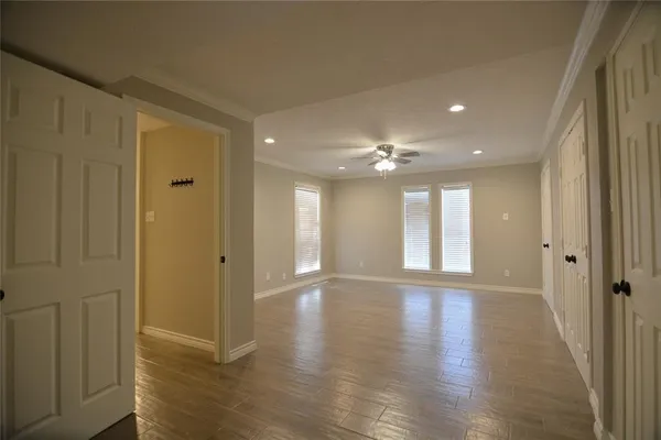 a view of an empty room with wooden floor and a window
