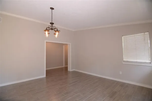 an empty room with wooden floor chandelier and windows