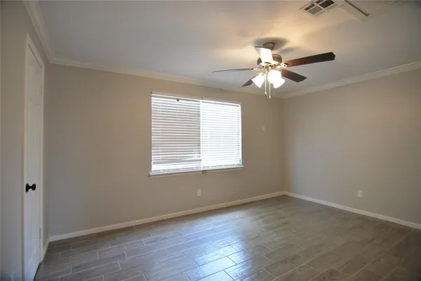 an empty room with wooden floor fan and windows