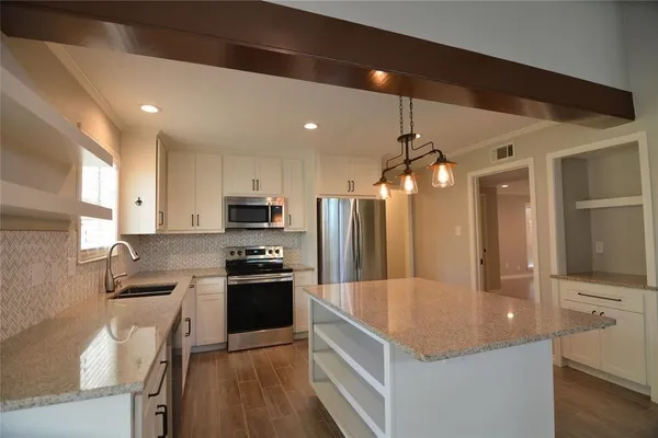 a kitchen with stainless steel appliances granite countertop a sink a stove and a refrigerator