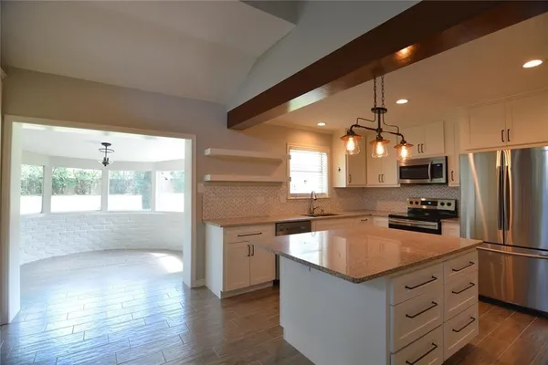 a kitchen with granite countertop a refrigerator a sink a stove and wooden floor