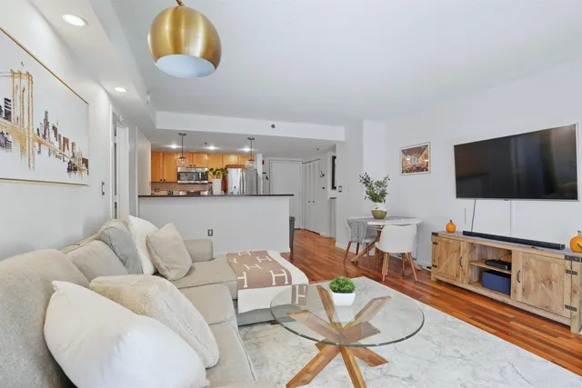 a living room with furniture a flat screen tv and kitchen view