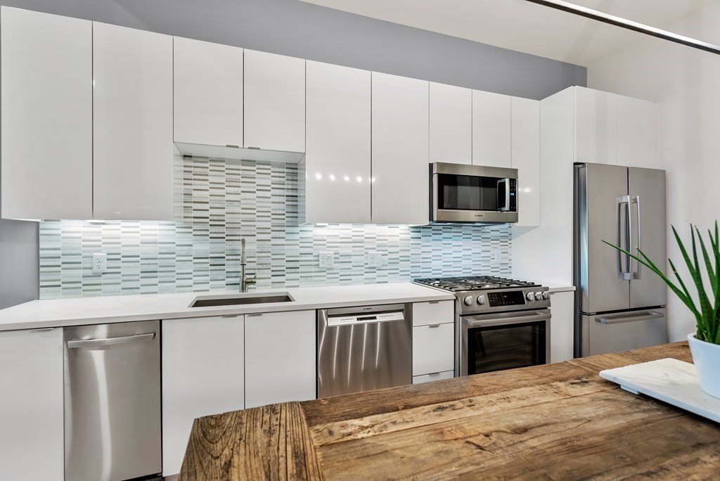 121 Portland Street, Unit 206 Boston, MA 02114 - Photo 5 of 35 a kitchen with stainless steel appliances granite countertop a stove a sink dishwasher and a refrigerator