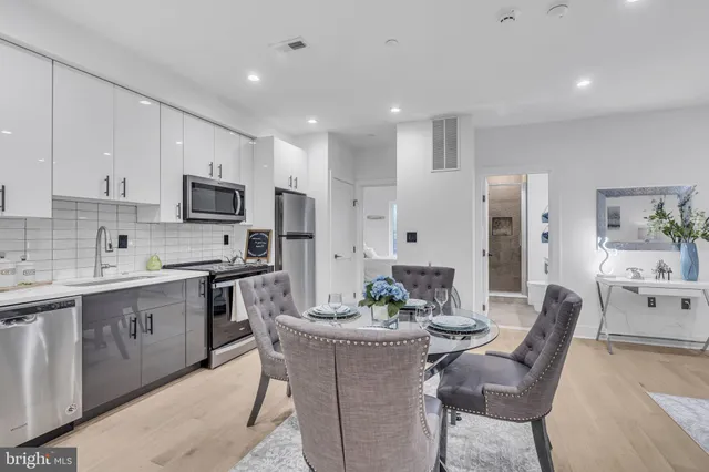 a kitchen with stainless steel appliances kitchen island granite countertop a dining table chairs sink and cabinets