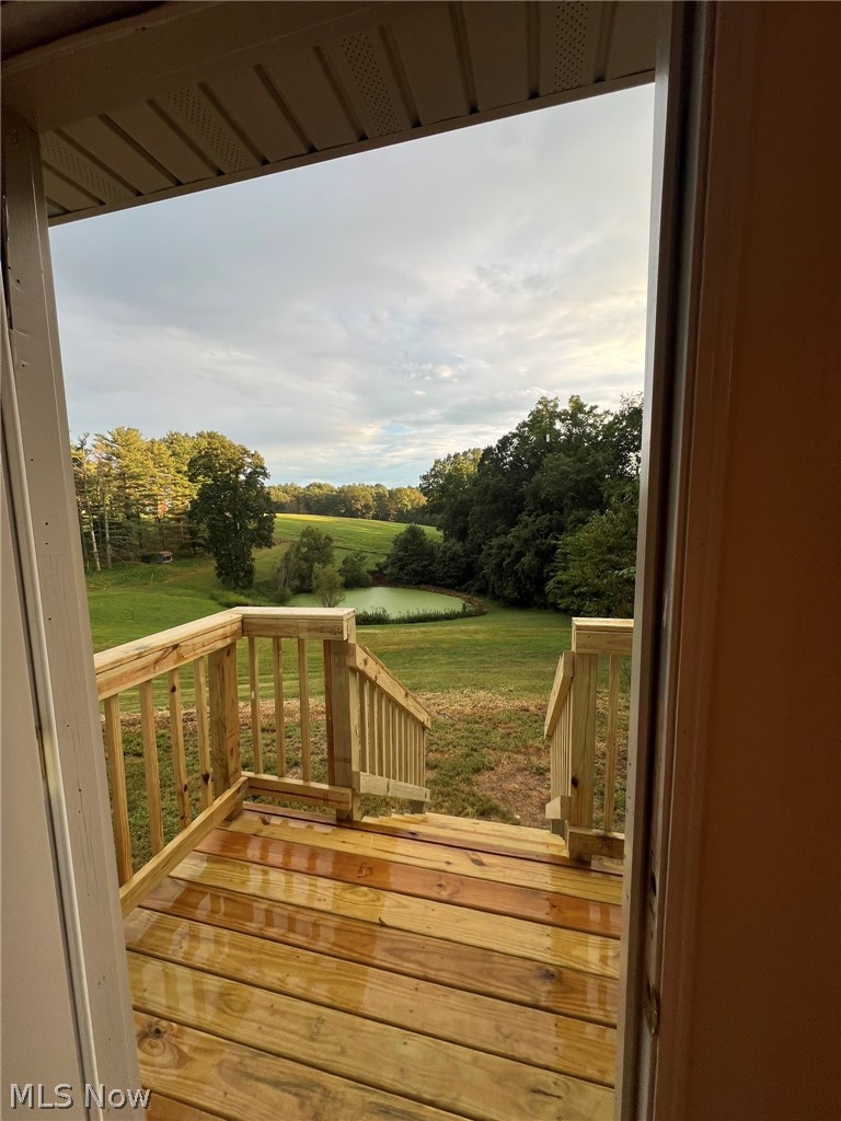 1105 Dutch Ridge Road Guysville, OH 45735 - Photo 22 of 33 New wood deck with natural finish, featuring a full railing system and stairs descending to a spacious green landscape