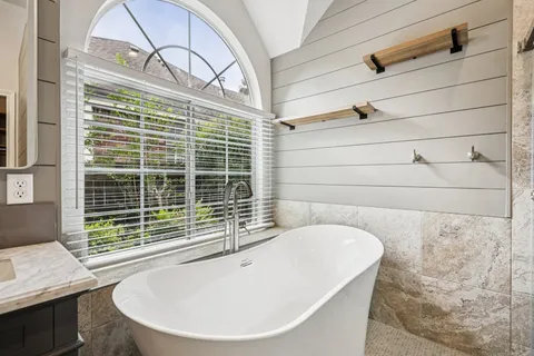 a bathroom with a bathtub and next to a window