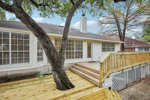 a view of a house with wooden deck and a large tree