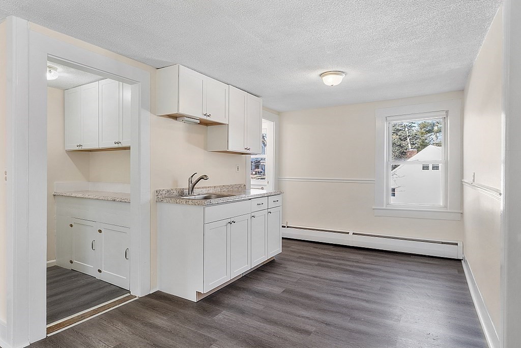 8 Main Street, Unit 2R Pepperell, MA 01463 - Photo 5 of 13 a kitchen with granite countertop white cabinets and white appliances