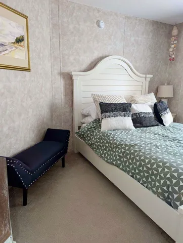 a bedroom with a bed chair and wall painting on the wall