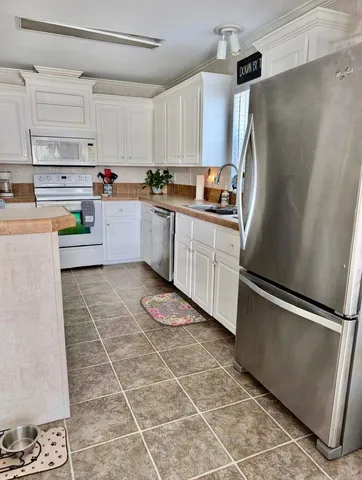 a kitchen with granite countertop a refrigerator a sink and white cabinets